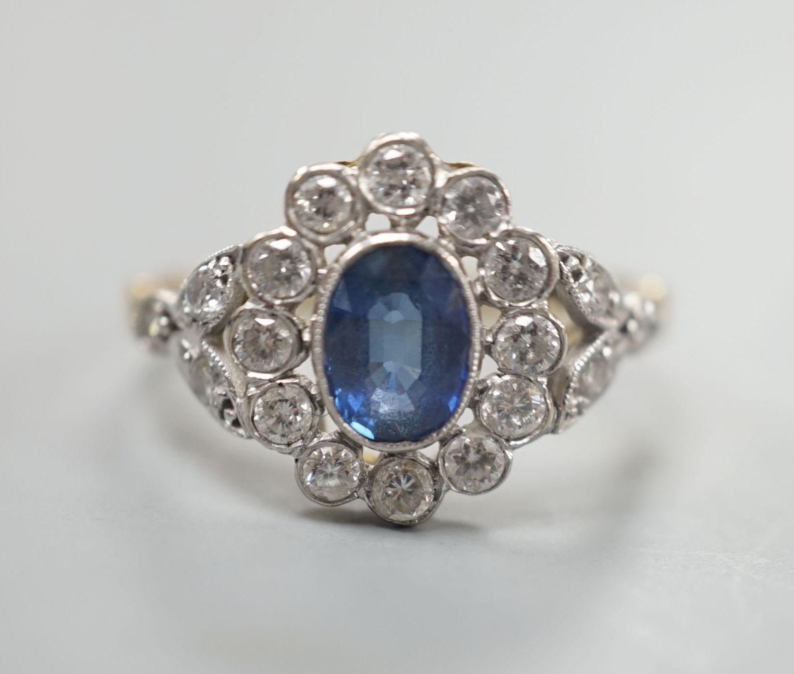 A yellow metal, sapphire and diamond set oval cluster ring, size T, gross weight 3.8 grams.